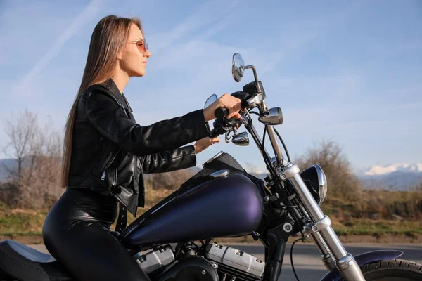 Beautiful woman riding motorcycle on sunny day