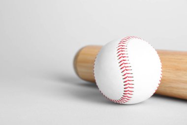 Wooden baseball bat and ball on light grey background, space for text. Sports equipment