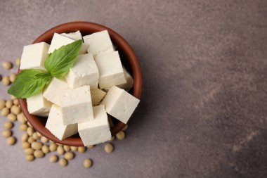 Delicious tofu cheese, basil and soybeans on brown textured table, flat lay. Space for text
