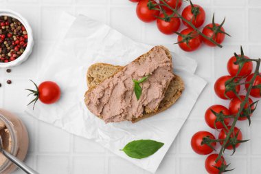 Delicious liverwurst sandwich and ingredients on white tiled table, flat lay
