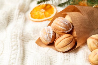 Delicious nut shaped cookies and dried orange slice on white knitted fabric, closeup. Space for text