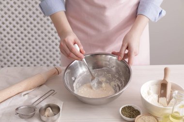 Woman making traditional grissini at white wooden table indoors, closeup