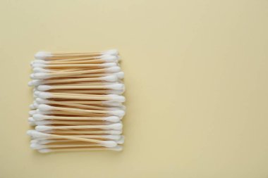 Many wooden cotton buds on beige background, flat lay. Space for text