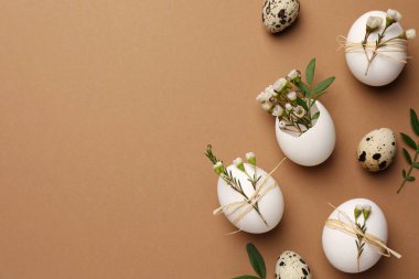 Happy Easter. Festive composition with eggs and floral decor on brown background, flat lay. Space for text.