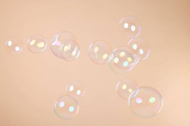 Many beautiful soap bubbles on beige background