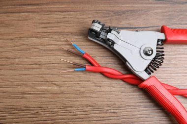 Cutters and stripped wire on wooden table, flat lay. Space for text