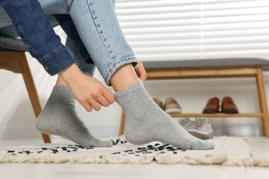 Woman putting on grey socks at home, closeup