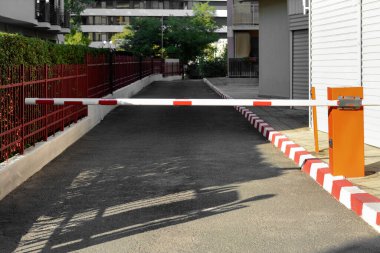 Closed boom barrier near road on sunny day outdoors