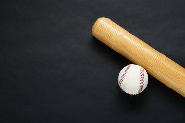 Wooden baseball bat and ball on black background, flat lay. Space for text