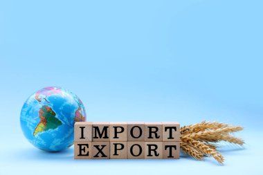 Words Import and Export made of wooden cubes, globe and ears of wheat on light blue background