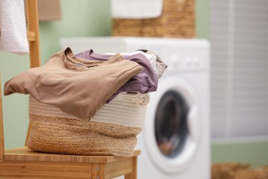Laundry basket filled with clothes on chair in bathroom, closeup. Space for text