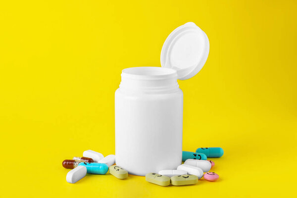 Различные антидепрессанты со счастливыми смайликами и медицинская банка на желтом фоне