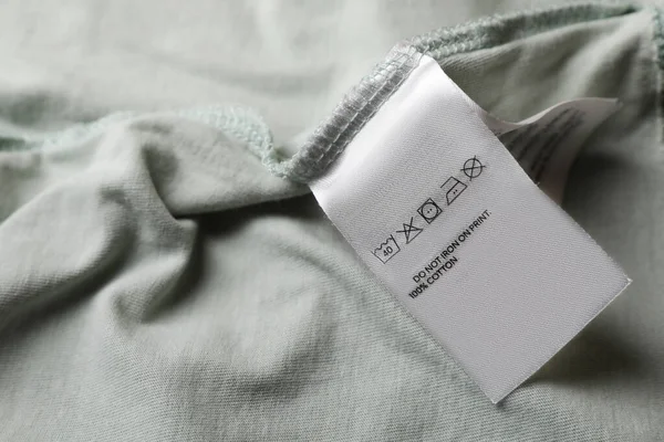 Clothing label on pale olive garment, closeup