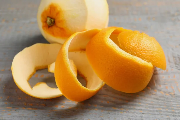 Peeled fresh orange with zest preparing for drying on wooden table, closeup