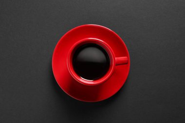 Red cup with aromatic coffee on black background, top view
