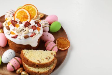 Traditional Easter cake with dried fruits and painted eggs on white table, space for text