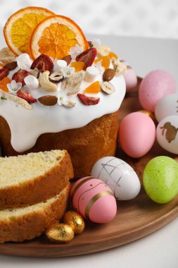 Traditional Easter cake with dried fruits and painted eggs on white table, closeup