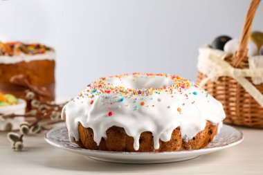 Delicious Easter cake decorated with sprinkles near painted eggs and willow branches on white wooden table