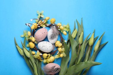 Flat lay composition with flowers and eggs on light blue background. Easter celebration