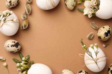 Frame made of eggs and natural decor on brown background, top view with space for text. Happy Easter