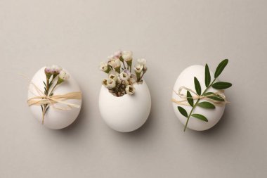 Festive composition with chicken eggs and natural decor on light grey background, flat lay. Happy Easter