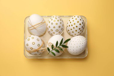 Festively decorated chicken eggs on yellow background, top view. Happy Easter