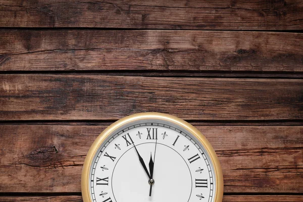 Clock showing five minutes until midnight on wooden table, top view with space for text. New Year countdown