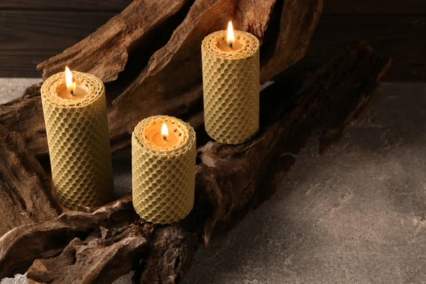 Beautiful burning beeswax candles on snag indoors