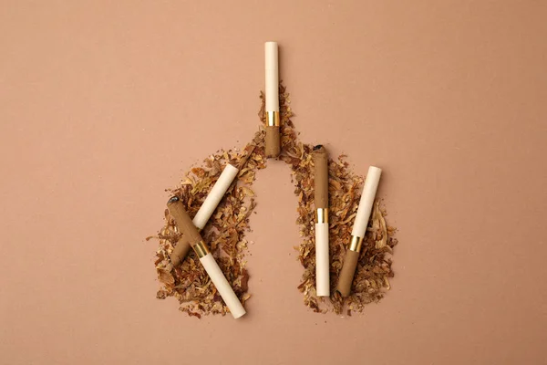 No smoking concept. Lungs made of dry tobacco and cigarettes on brown background, flat lay