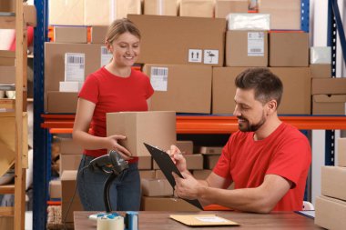 Post office workers checking parcel barcode indoors