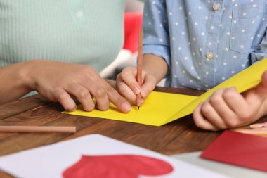 Little girl with her mother making beautiful greeting card at home, closeup