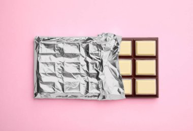 Tasty chocolate bar on pink background, top view