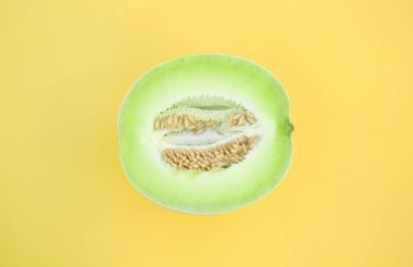 Half of fresh ripe honeydew melon on yellow background, top view