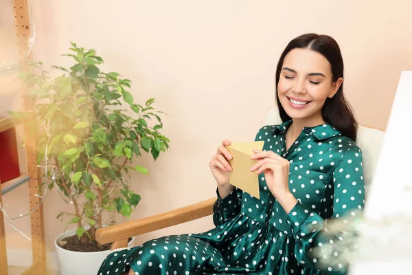 Happy woman holding greeting card in living room