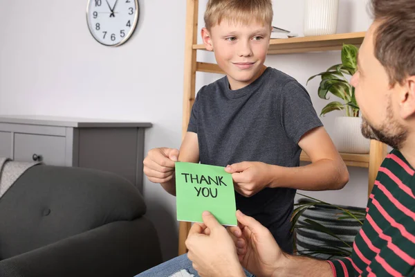 Man receiving greeting card from his son at home
