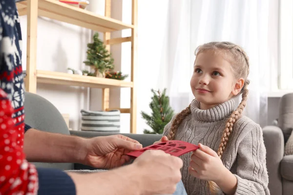Man receiving greeting card from his daughter at home