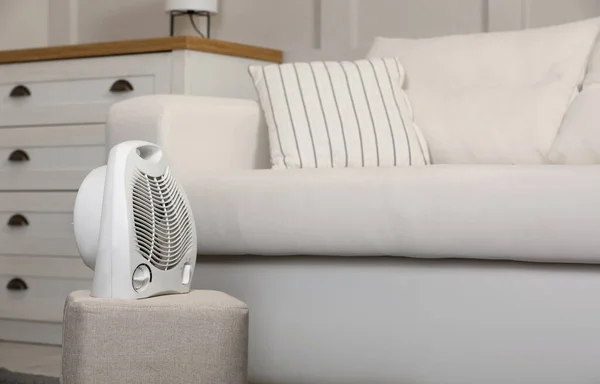 Electric fan heater on pouf in living room