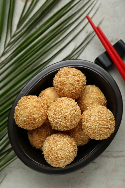 Delicious sesame balls and green leaf on textured table, flat lay