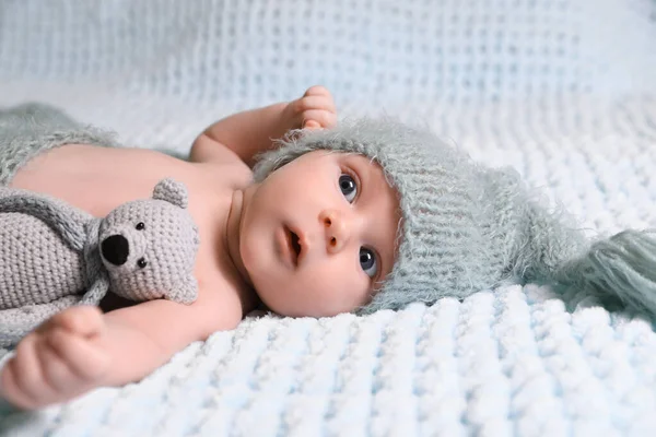 Cute newborn baby with crochet toy on light blue blanket