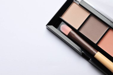 Beautiful eye shadow palette with brush on white table, top view. Space for text