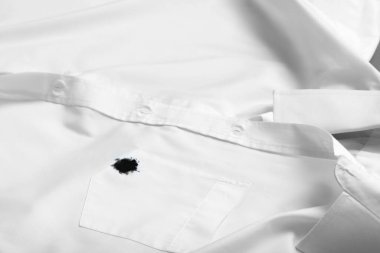 Stain of black ink on white shirt, closeup. Space for text
