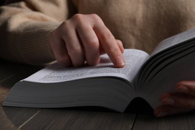 Woman with Bible at wooden table, closeup