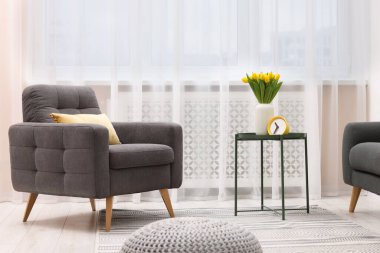 Spring atmosphere. Stylish living room interior with comfortable furniture and bouquet of beautiful yellow tulips
