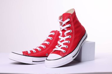 Pair of new red stylish high top plimsolls on white background