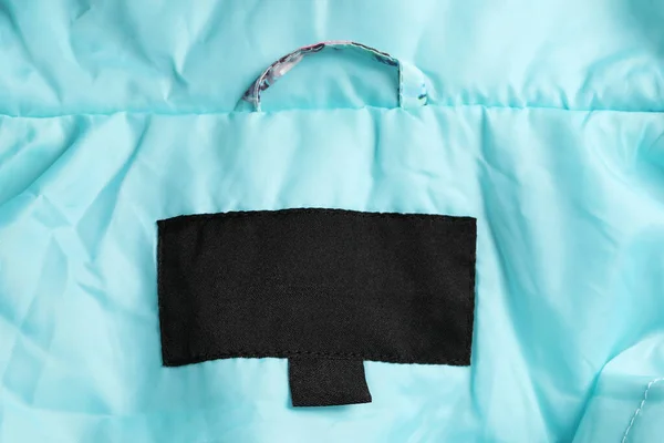 Clothing label on turquoise garment, top view