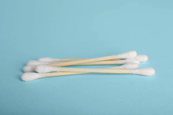 Wooden cotton buds on light blue background