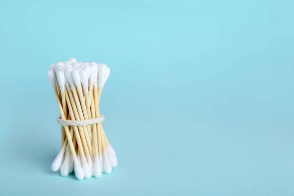 Bunch of wooden cotton buds on light blue background. Space for text
