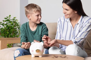 Boy and his mother with piggy bank at home