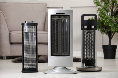 Different modern infrared heater on floor in cozy room