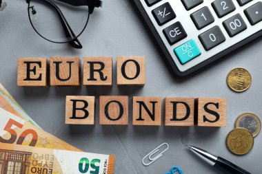 Flat lay composition with banknotes and word Eurobonds made of wooden cubes on grey table
